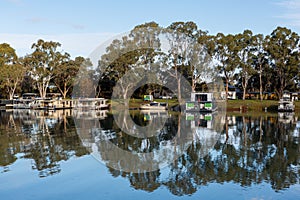 The reflection of house boats and tree on a calm river murray located in the river land at Berri South Australia on 20th June 2020