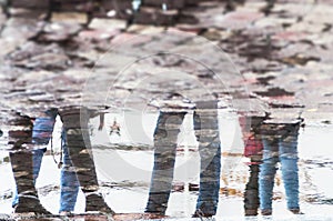 reflection of legs of people in a paddle on cobblestone surface in the street