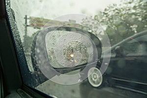 Reflection of lights in a car`s side mirror on a rainy night