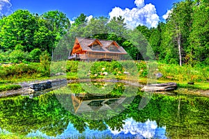 Reflection of a log cabin in the near by pond HDR