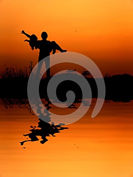 Reflection of Man and Woman love silhouette in sunset