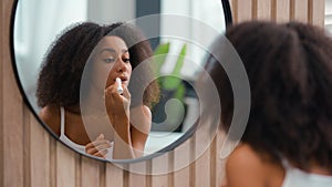 Reflection in mirror in bath home bathroom African American beauty female make-up apply natural smooth moisturize