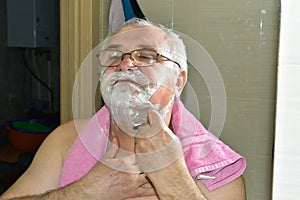 Reflection in the mirror of a man shaving his neck in the bathroom.