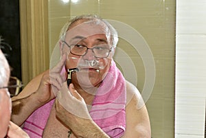 Reflection in the mirror of a man shaving in the bathroom.