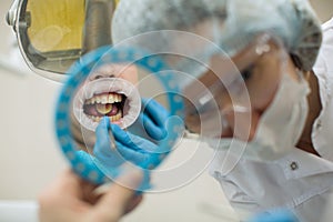 Reflection in the mirror mouth and teeth, woman dentist doing teeth checkup of boy