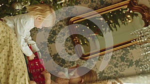 Reflection in the mirror, two girls with blond hair playing with gift