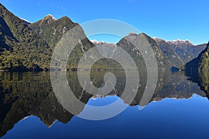 Reflection of mountains along the fiord of Doubtful Sound in Fiordland National Park in New Zealand