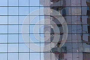 Reflection of a multi-storey building in the glass facade of a modern skyscraper