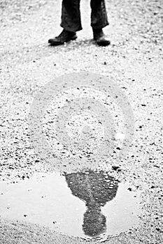 Reflection of obscured face in puddle