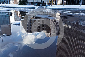 Reflection of office buildings in a puddle on the ground
