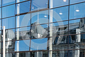 Reflection of an old building in a modern glass facade, contrast