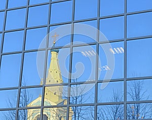 Reflection of old cathedral in glass wall of the modern building
