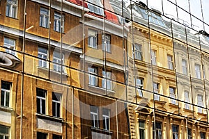reflection of old downtown houses in a modern glass facade