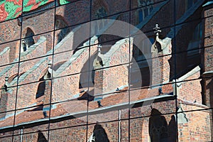 Reflection of an old, Gothic church with a multi-color roof