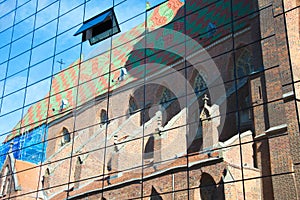 Reflection of an old, Gothic church with a multi-color roof