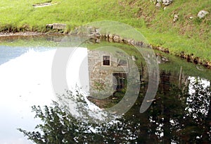 Reflection of an old mountain home on pond
