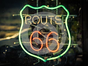 the reflection of an old route 66 sign is seen through the glass