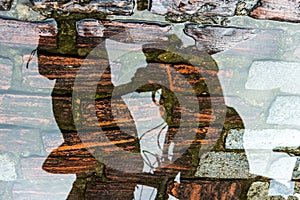 Reflection of person and bicycle in a puddle of rainwater in the river