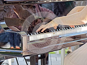 Reflection in the piano of a woman`s hands during her execution