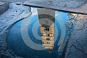 Reflection of Pistoia Cathedral bell tower in the puddle in Tuscany, Italy