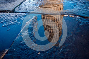 Reflection of Piza Tower in water after rain. Italy