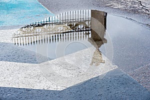 Reflection in puddle after rain of decorative historic metal fence . Mysterious abstract, gate entrance in dreams