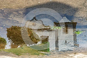 Reflection in a puddle of rainwater from a Catholic church and a tree