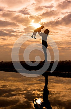 Reflection Silhouette of mother with her toddler against the sun