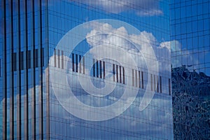 Reflection of the sky and clouds in the glass wall of a high-rise building. Glass wall of a skyscraper. Mirrored wall of