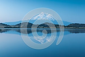 A reflection of snow capped Mount Shasta in a clear water in lake  at sunrise in California State, USA.  Mount Shasta is a volcano