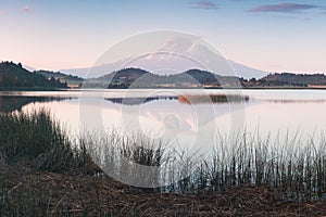 A reflection of snow capped Mount Shasta in a clear water in lake  at sunrise in California State, USA.  Mount Shasta is a volcano photo