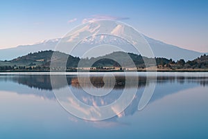 A reflection of snow capped Mount Shasta in a clear water in lake  at sunrise in California State, USA.  Mount Shasta is a volcano photo