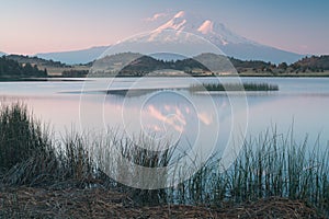 A reflection of snow capped Mount Shasta in a clear water in lake  at sunrise in California State, USA.  Mount Shasta is a volcano photo