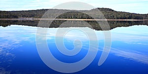 Reflection on still water of Australian forest and blue sky