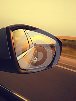 Reflection of sunny road at the car side mirrow. Rear view mirror reflection on sun down