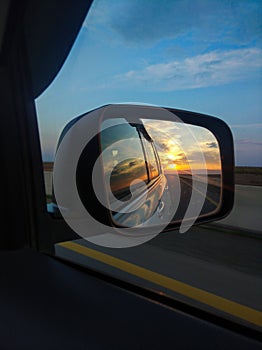 Reflection of the sunset in the rearview mirror of a car