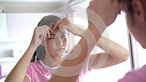 Reflection of teenage girl with ponytail popping zits close
