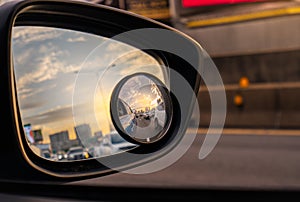 Reflection of traffic flow on asphalt road in side mirror of blue SUV. Car wing mirror with convex mirror for safety driving. View