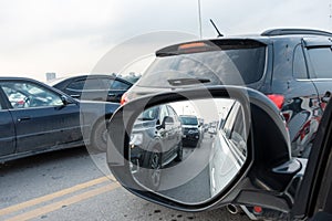 Reflection of traffic flow in left side rear view mirror at rush hour