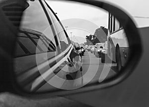 Reflection of a traffic jam in a sideview mirror. old black and white photography filter applied