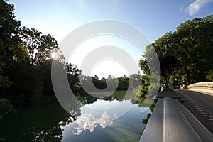 Reflection of trees and bridge in summertime with blue sky