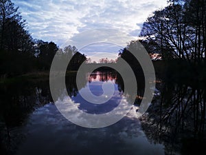 Reflection of trees, clouds and sunset in the river