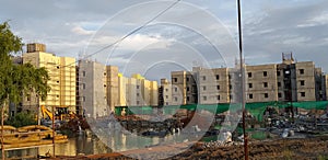 Reflection of under construction modern housing buildings over stagnant rain water at a construction site.
