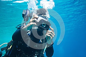 The reflection of an under water photographer`s subject is reflected in the lens of his camera