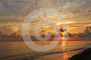 Reflection of vivid sunset sky over sea. Colorful sunrise with clouds over ocean. Beautiful nature background - orange sunset.