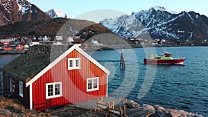 Reflection in the water. Snowy mountains, fishing village. Bright red houses on the ocean. Lofoten islands in Norway