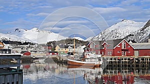 Reflection in the water. Snowy mountains, fishing village. Bright red houses on the ocean. Lofoten islands in Norway