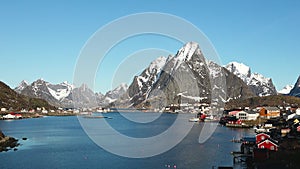 Reflection in the water. Snowy mountains, fishing village. Bright red houses on the ocean. Lofoten islands in Norway