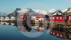 Reflection in the water. Snowy mountains, fishing village, red rorbu houses, and their peaceful reflections on the water