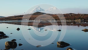 Reflection in the water. Snowy mountains, fishing village, red rorbu houses, and their peaceful reflections on the water